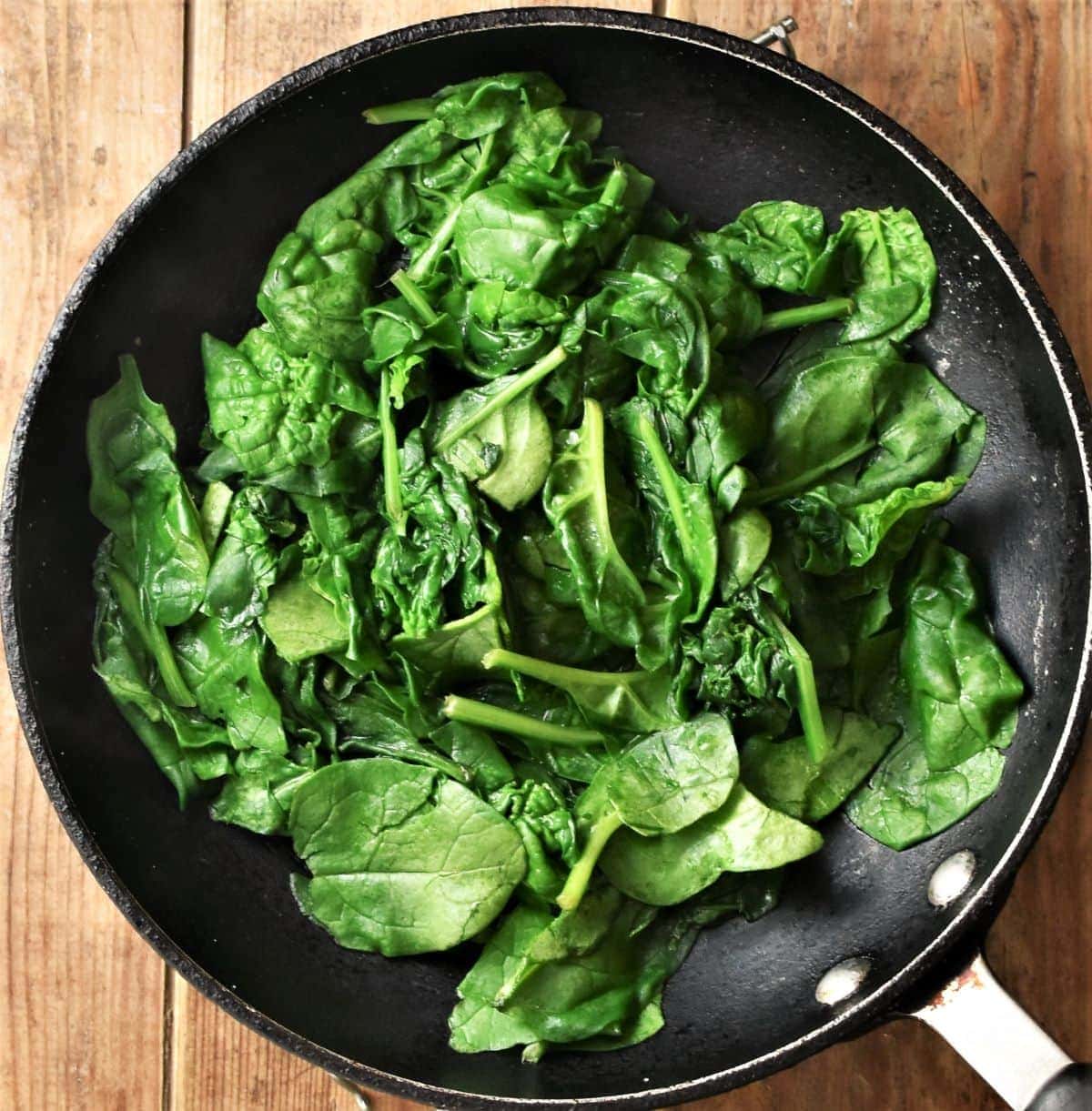 Fresh spinach, partly wilted, in skillet