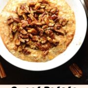 Overnight oats topped with pecans in white bowl with spoon, pecans and cinnamon sticks in background.