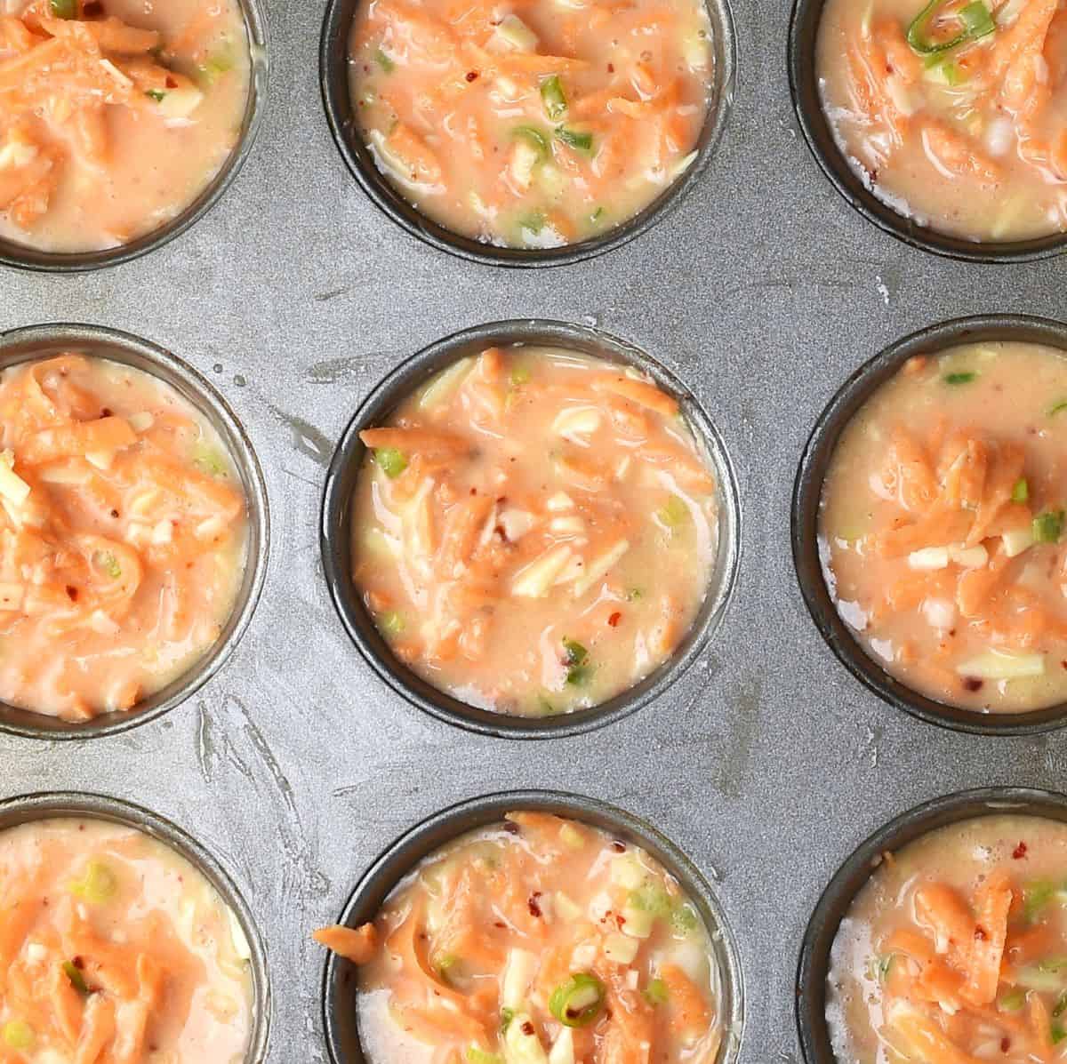 Top down view of muffin pan filled with sweet potato and egg muffin batter.