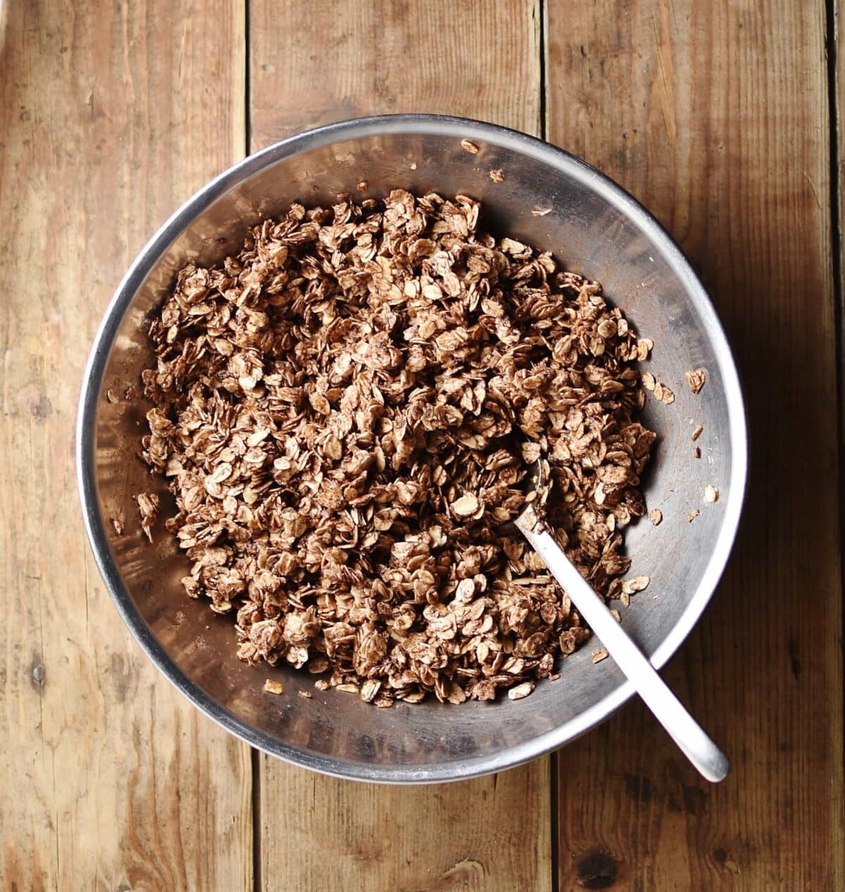 Chocolate oats with spoon in metal bowl.