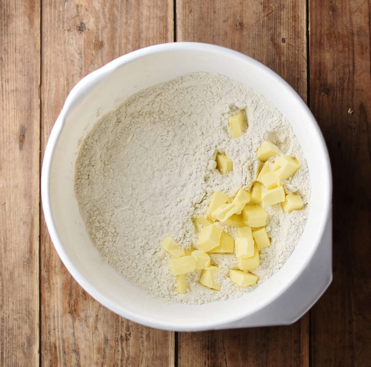 Flour and cubed butter inside large white bowl.