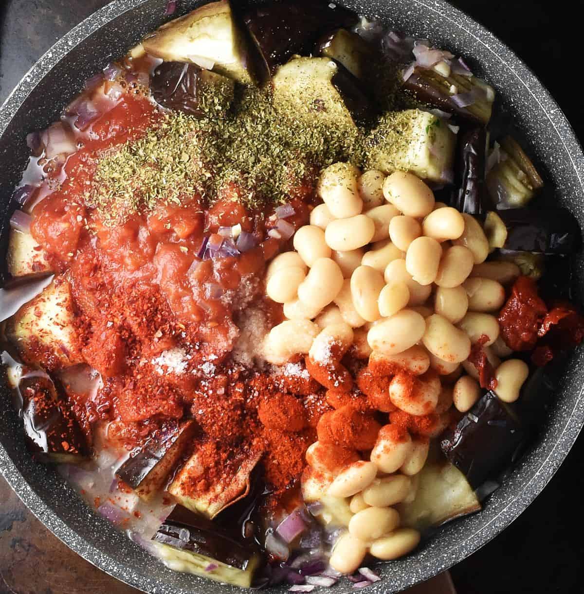 Eggplant chunks, tomatoes, beans, herbs and spices in large pan.