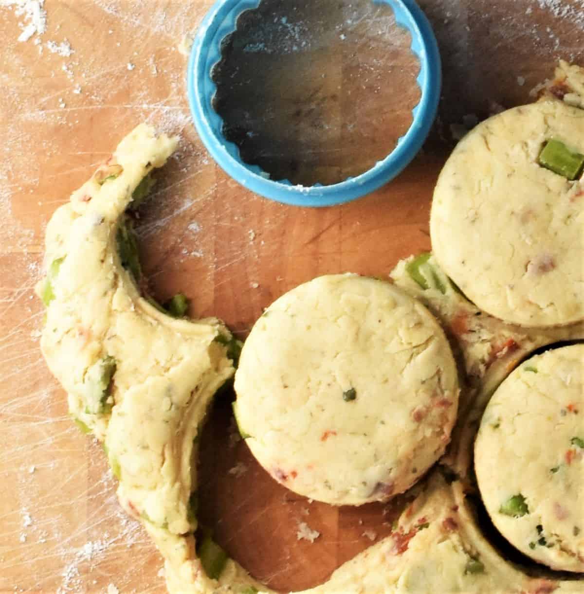 Cutting out dough rounds with blue pastry cutter.