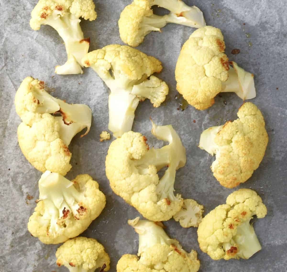 Roasted cauliflower florets on top of parchment.