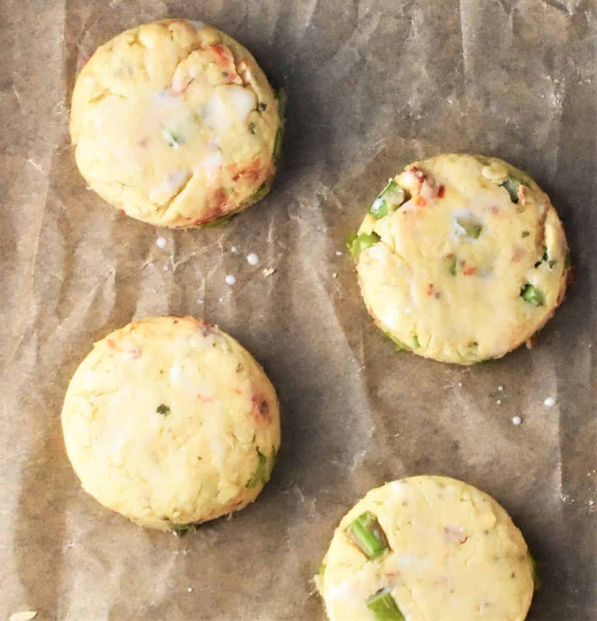 4 sundried tomato unbaked scones on top of parchment.