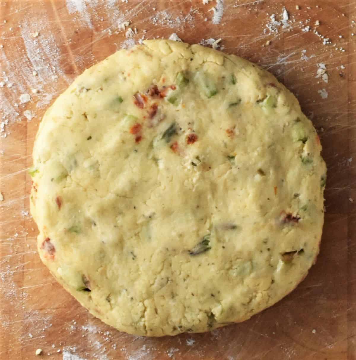 Round flattened scones dough on top of floured board.