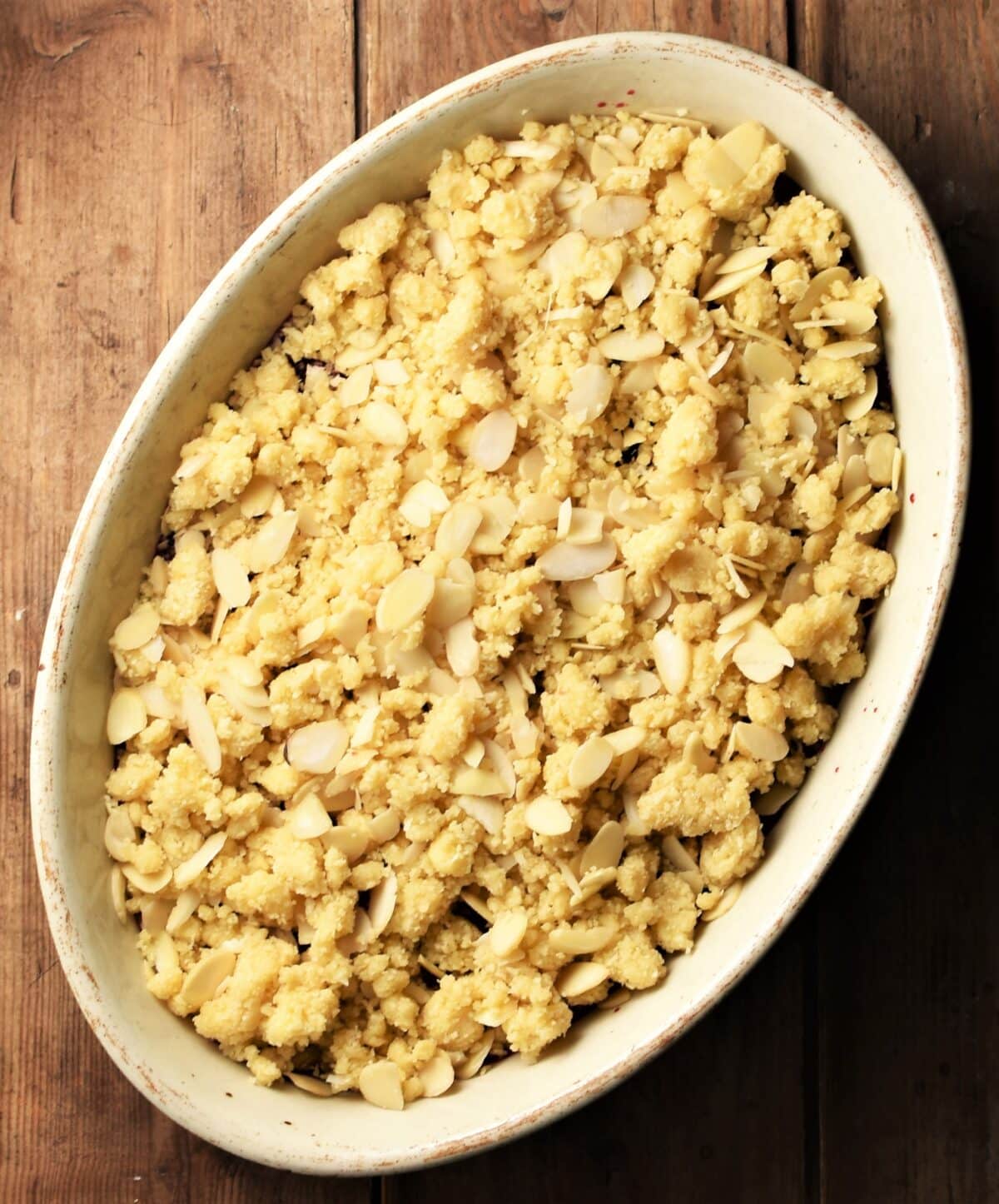 Unbaked crumble in white oval dish.