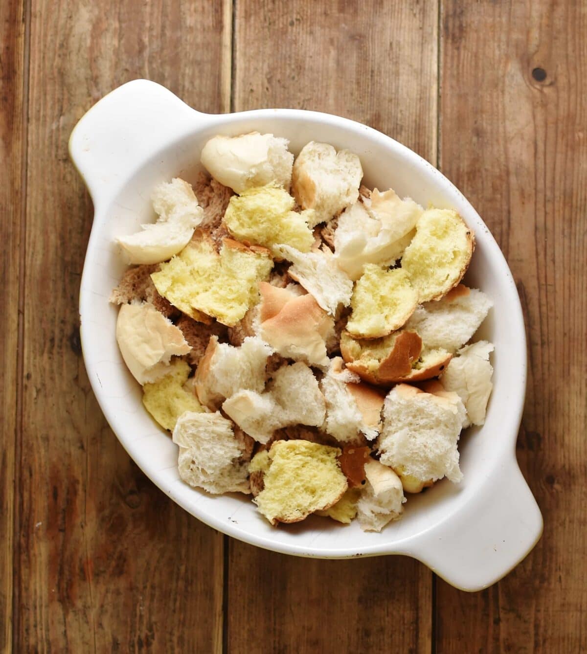 Torn up bread inside white oval dish.