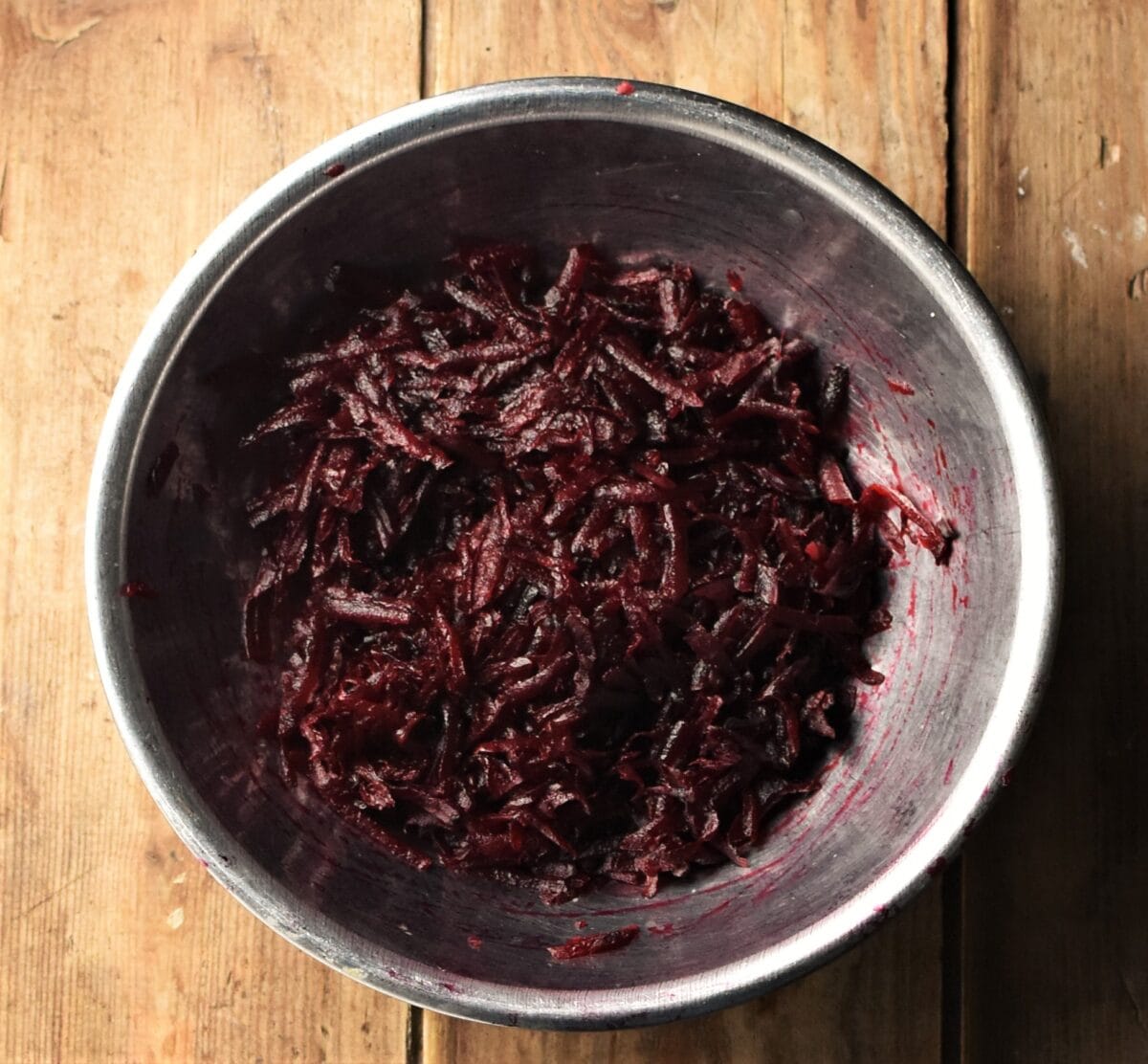 Grated beetroot in metal bowl.