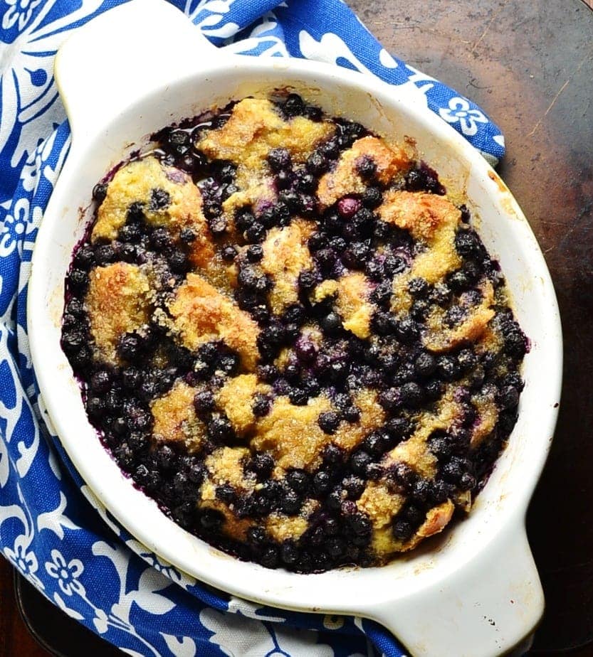 Top down view of blueberry french toast in white oval dish and blue-and-white cloth around it.