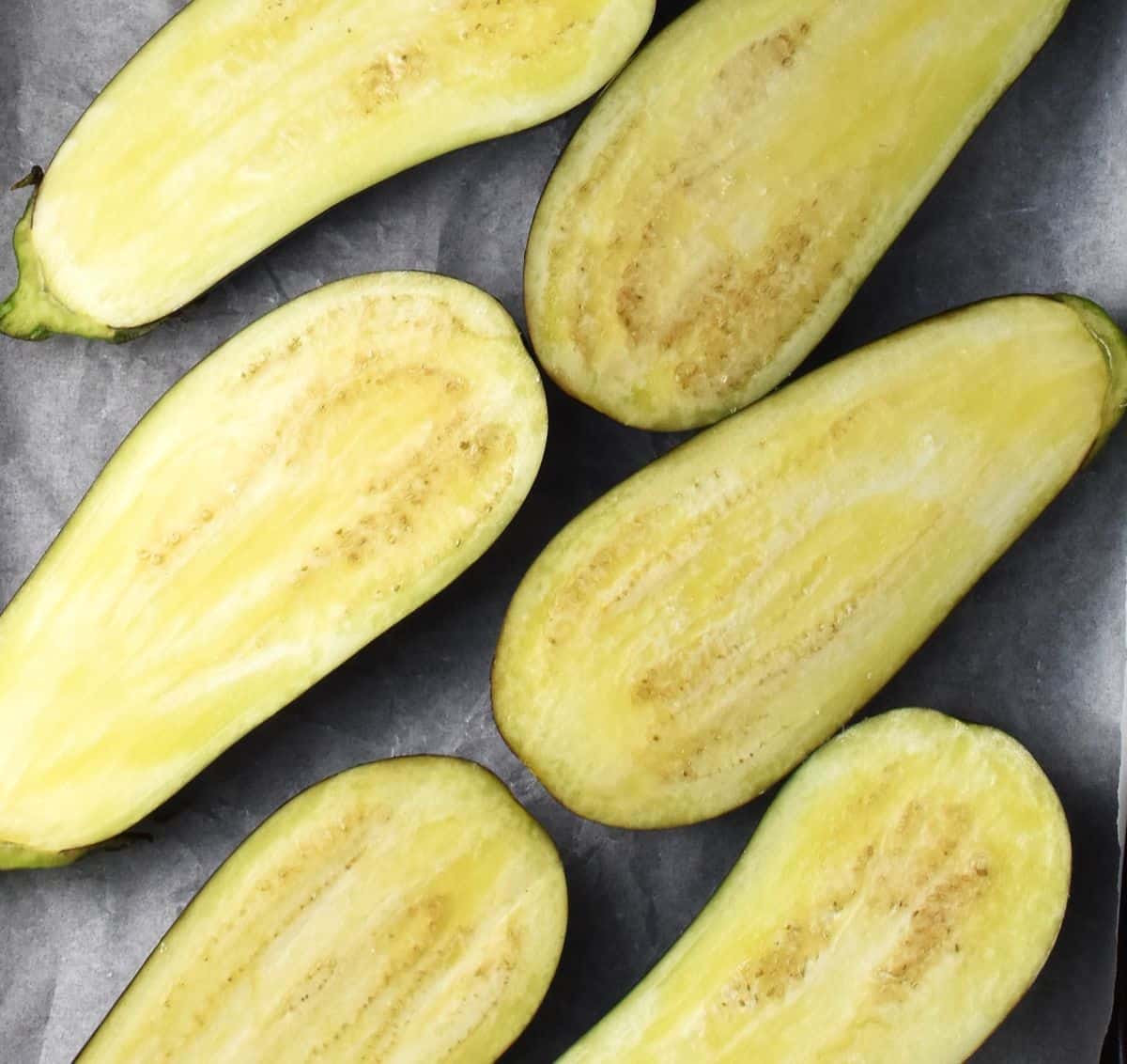 Top down view of eggplant halves on top of parchment paper.