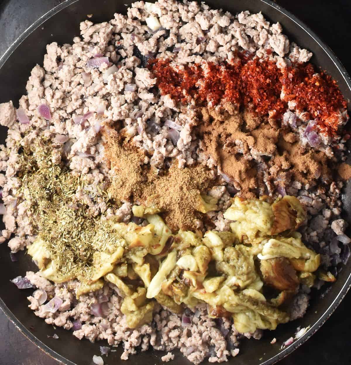 Top down view of cooked ground turkey with spices and eggplant pulp in large pan.