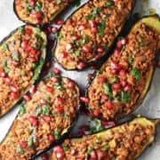 Close-up top down view of eggplant halves stuffed with turkey on parchment paper.