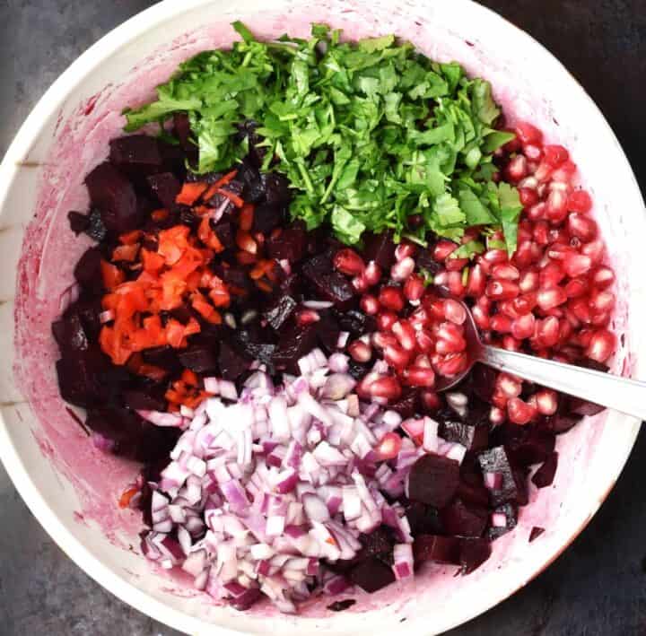 Assembling beet salsa ingredients in large bowl with spoon.