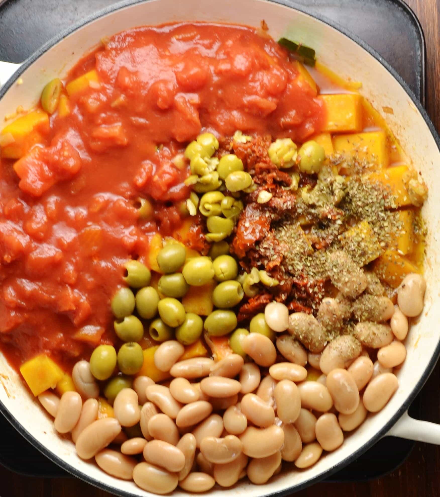 Top down view of vegan butternut squash casserole ingredients in large shallow white dish on top of oven tray.