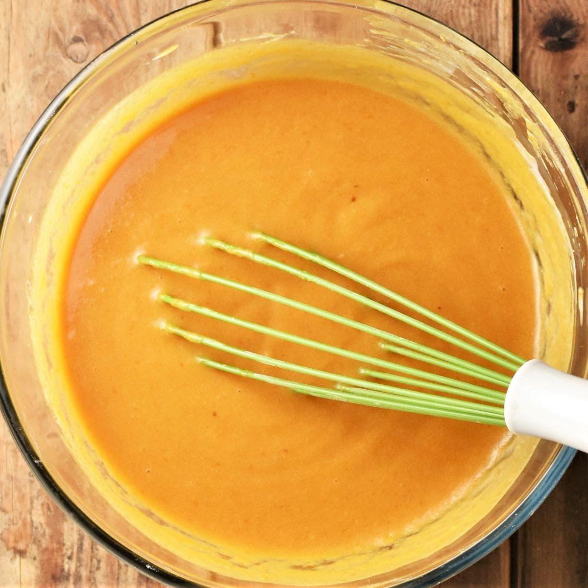 Pumpkin muffin batter mixture with whisk in bowl.