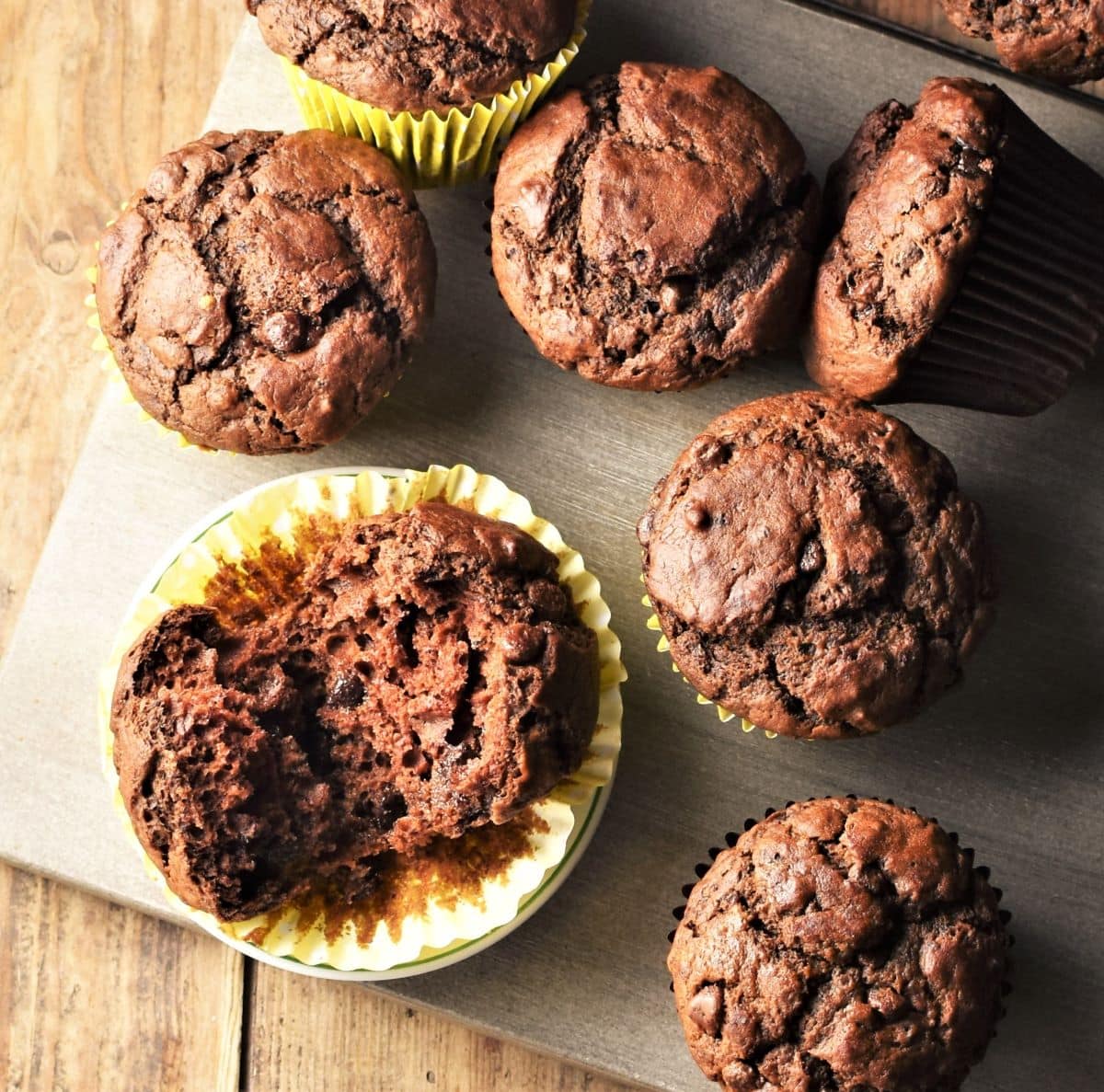 Pumpkin chocolate muffins in paper liners on top of grey board.
