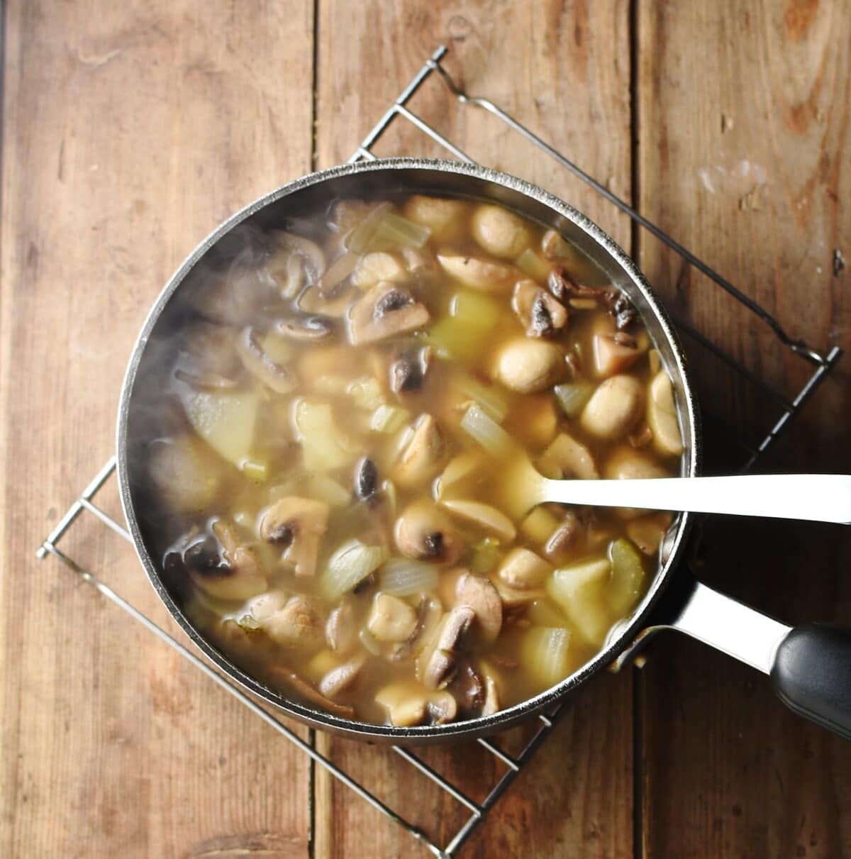 Chunky mushroom potato soup in large pot with spoon.