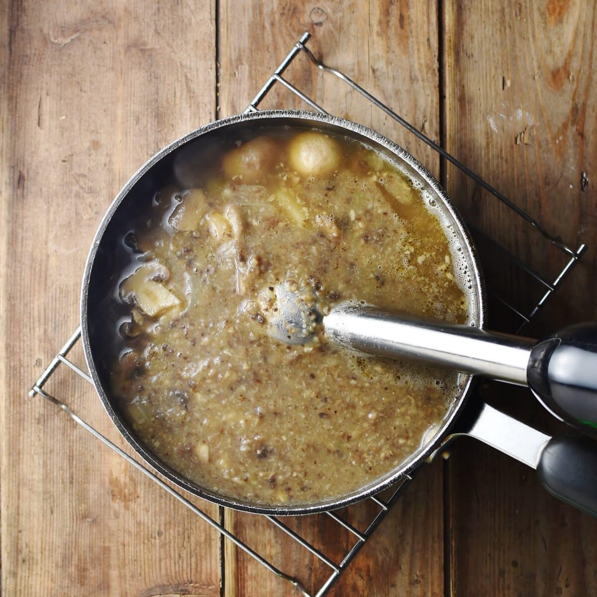 Partly pureed mushroom soup with stick blender in large pot.
