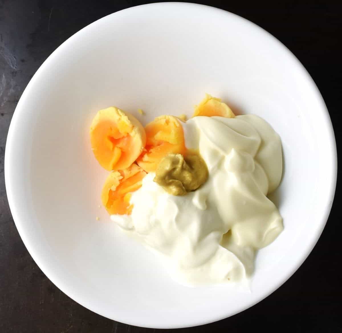 Ingredients for deviled egg sauce in white bowl.