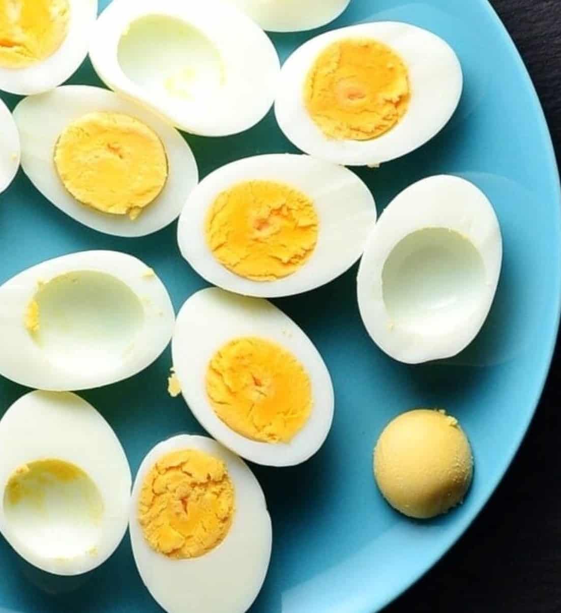 Top down view of halved hard-boiled eggs on blue plate.