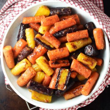 Top down view of miso glazed carrots in white bowl.