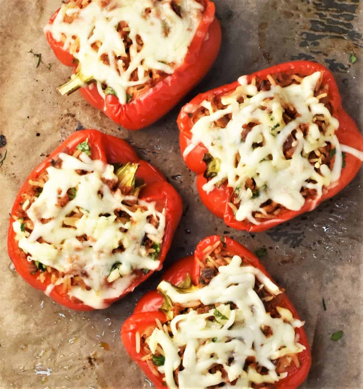 4 baked stuffed peppers with melted cheese on top.