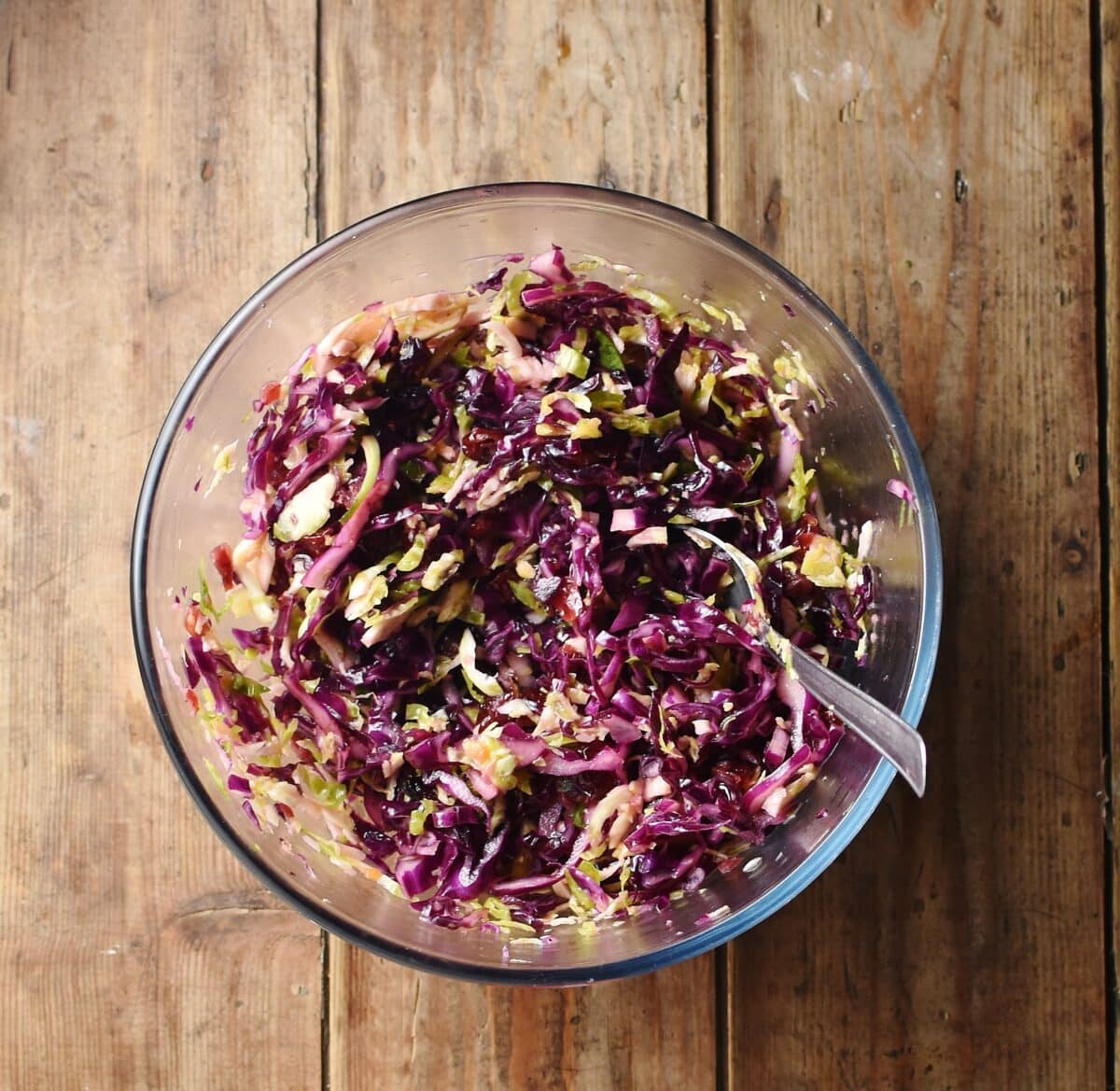 Christmas slaw in mixing bowl with spoon.