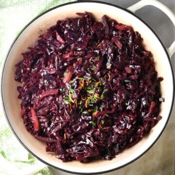 Top down view of braised red cabbage in large shallow white pan.