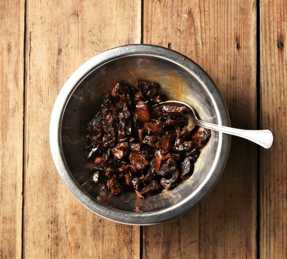 Chopped dates in small metal bowl with spoon.