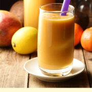 Side view of sweet potato smoothie on white plate with fruit in background.