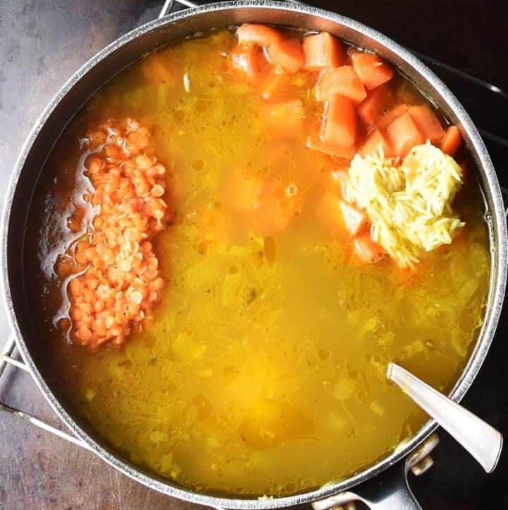 Soup with red lentils, rice and carrots in pot.