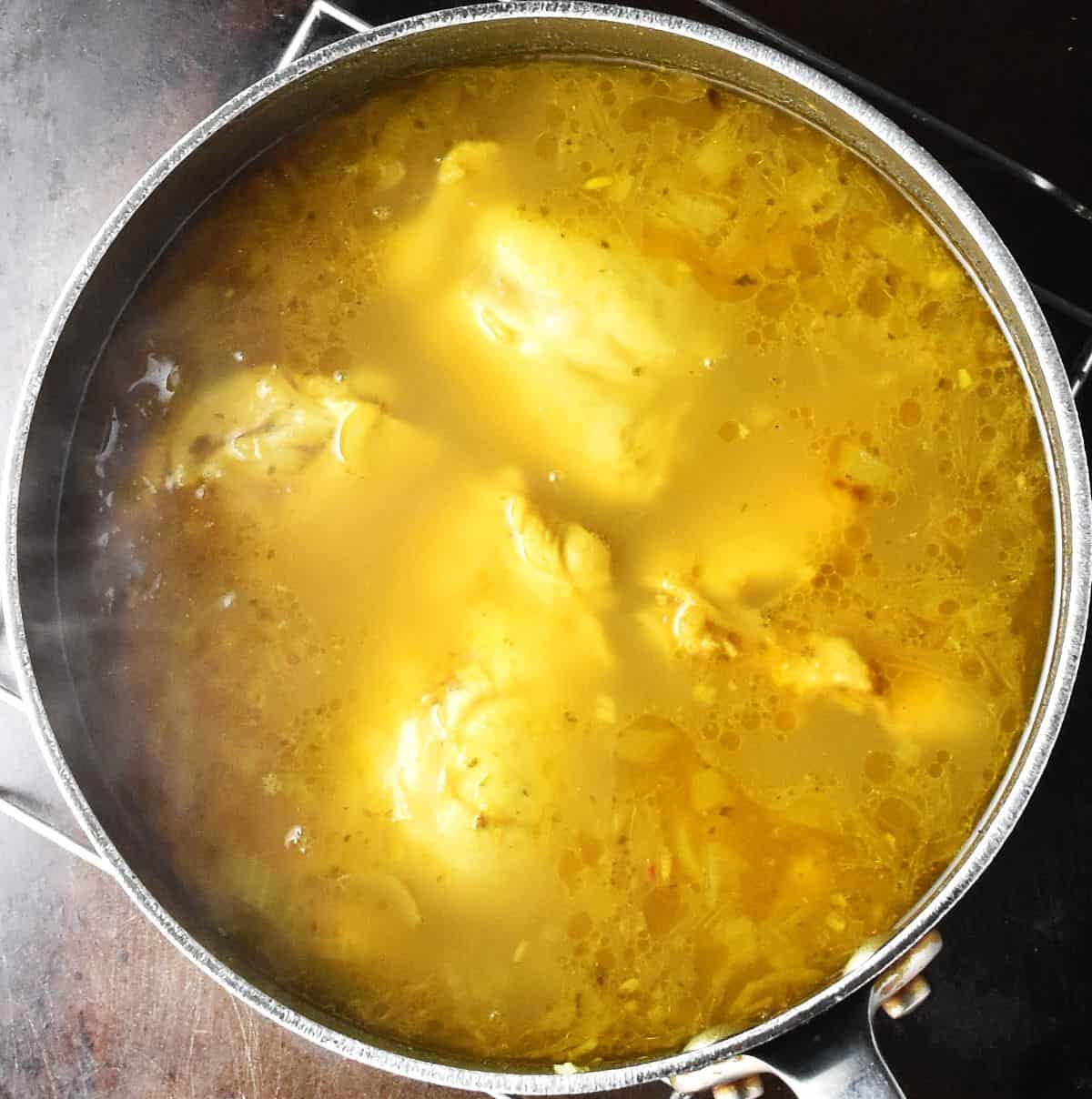 Top down view of curried chicken soup in pot.