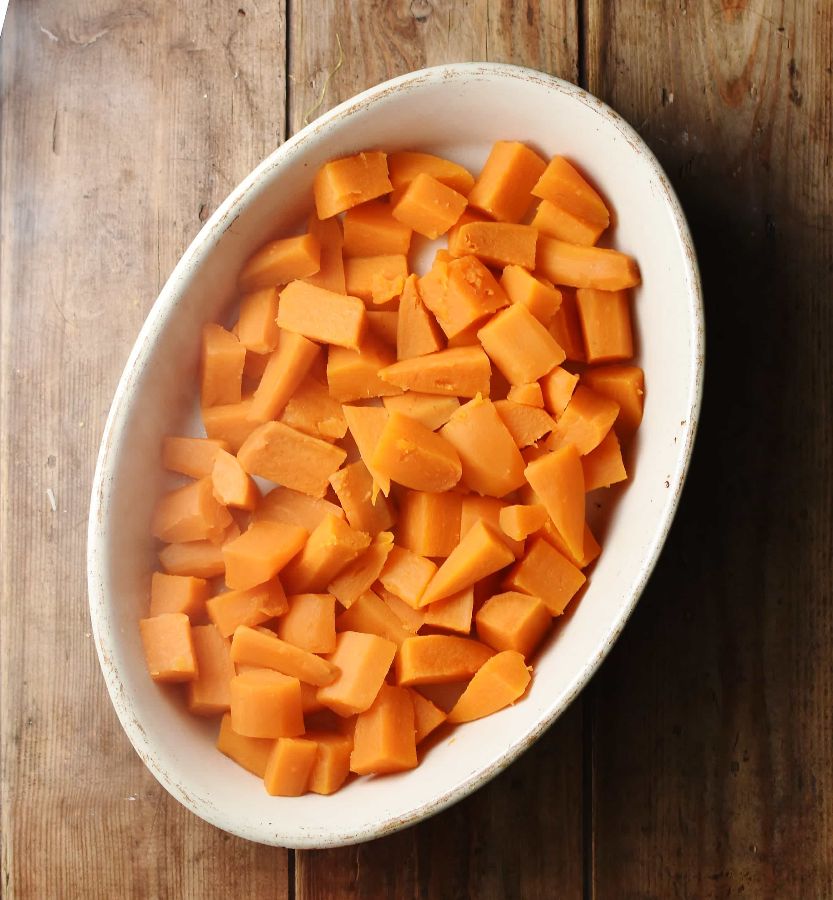 Cubed cooked sweet potato in white oval dish.
