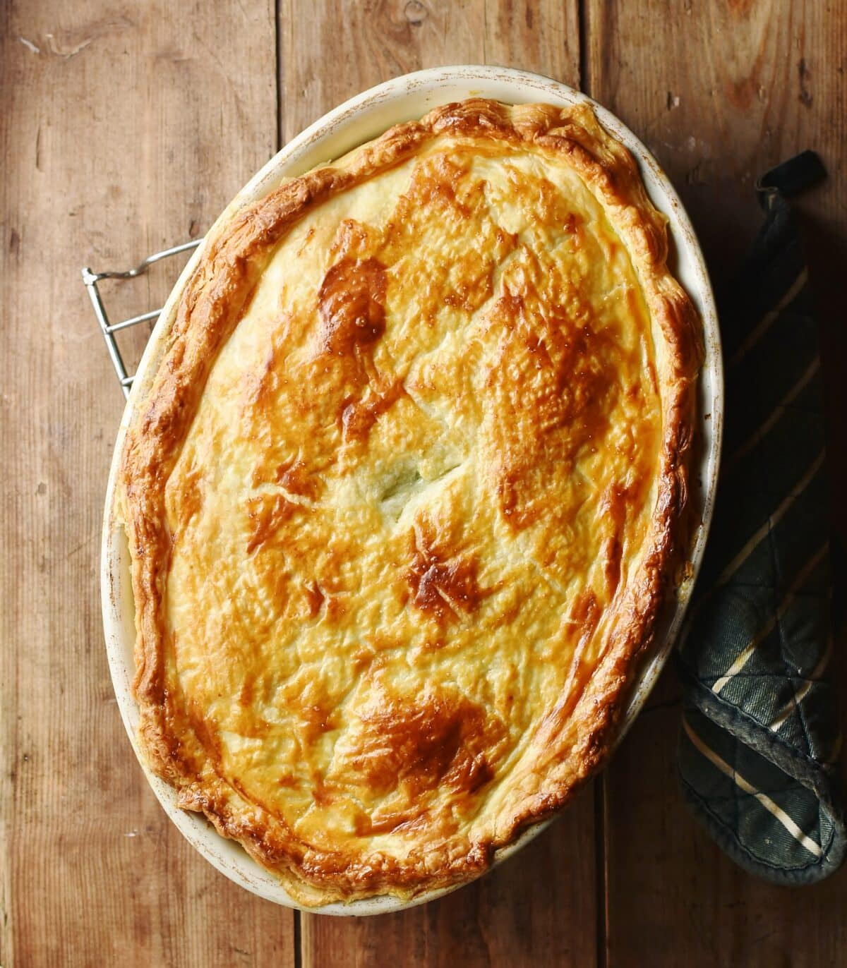 Pie in oval dish with golden brown pastry on top.