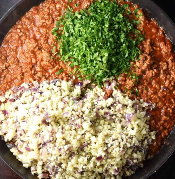Ground meat mixture with cauliflower rice and parsley in pan.
