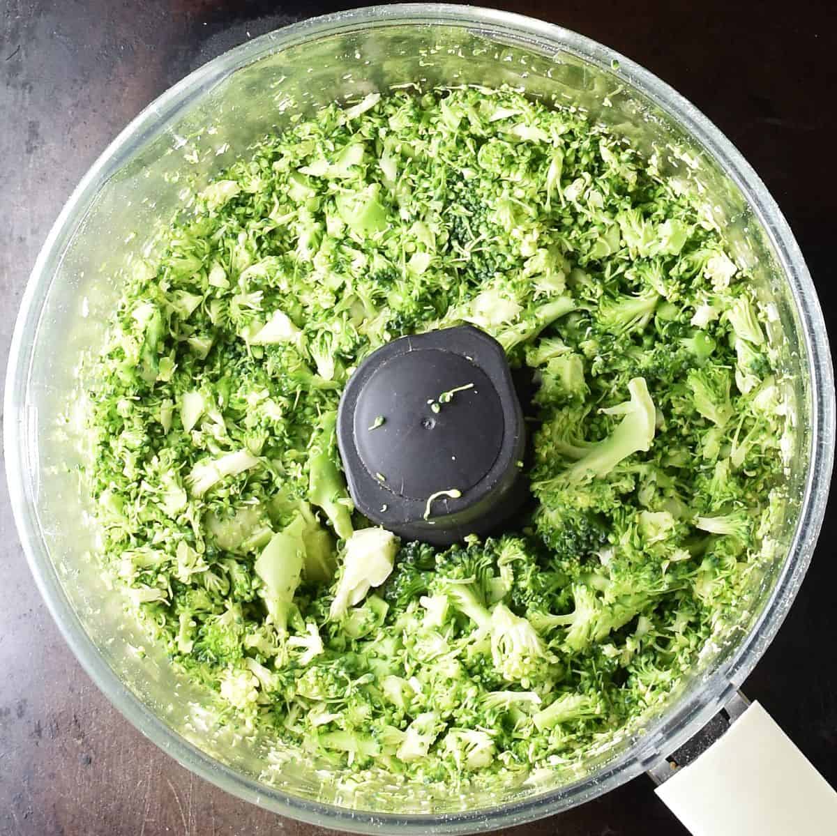 Top down view of chopped broccoli in blender bowl.