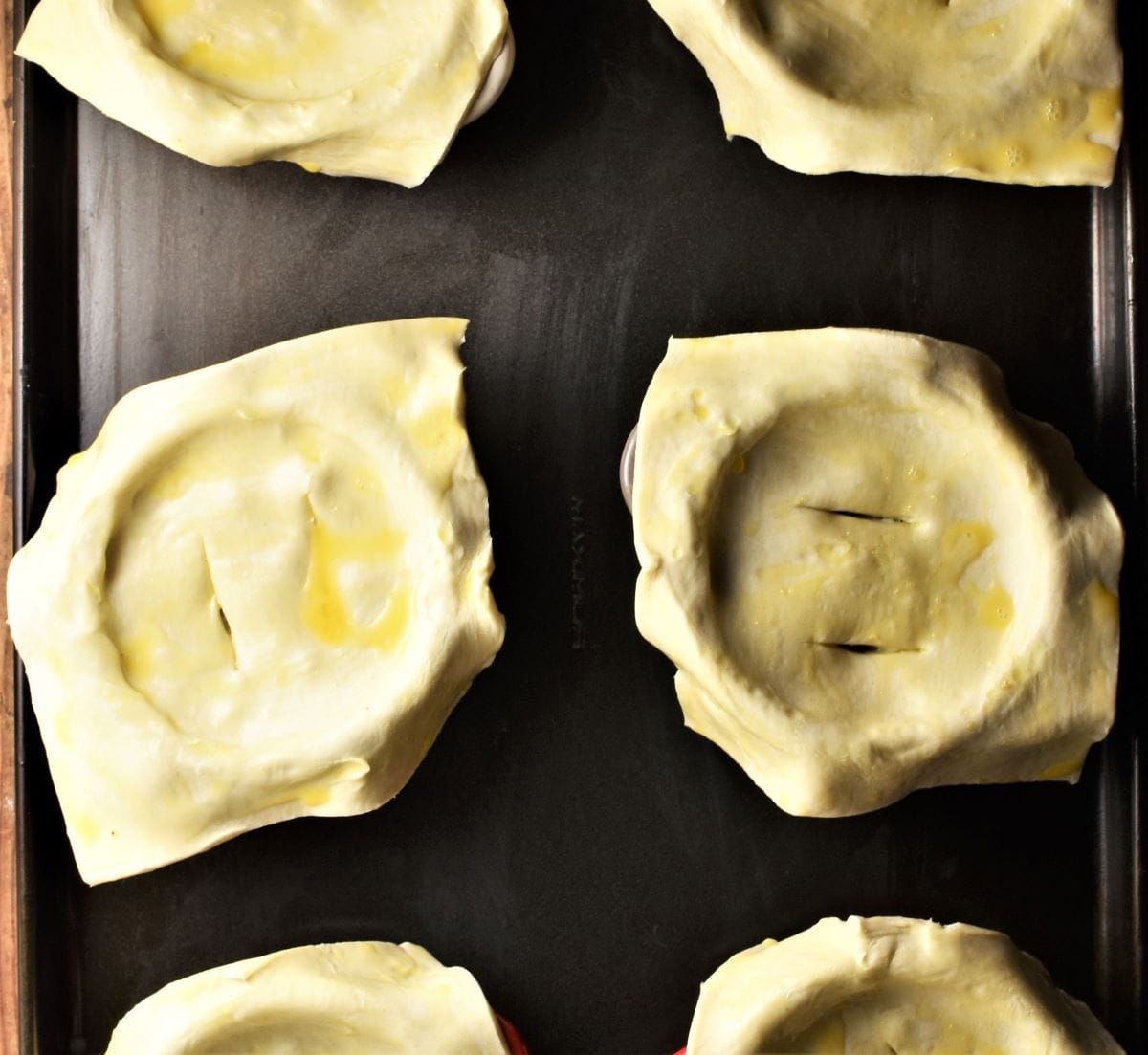 Uncooked pies with pastry squares on top.