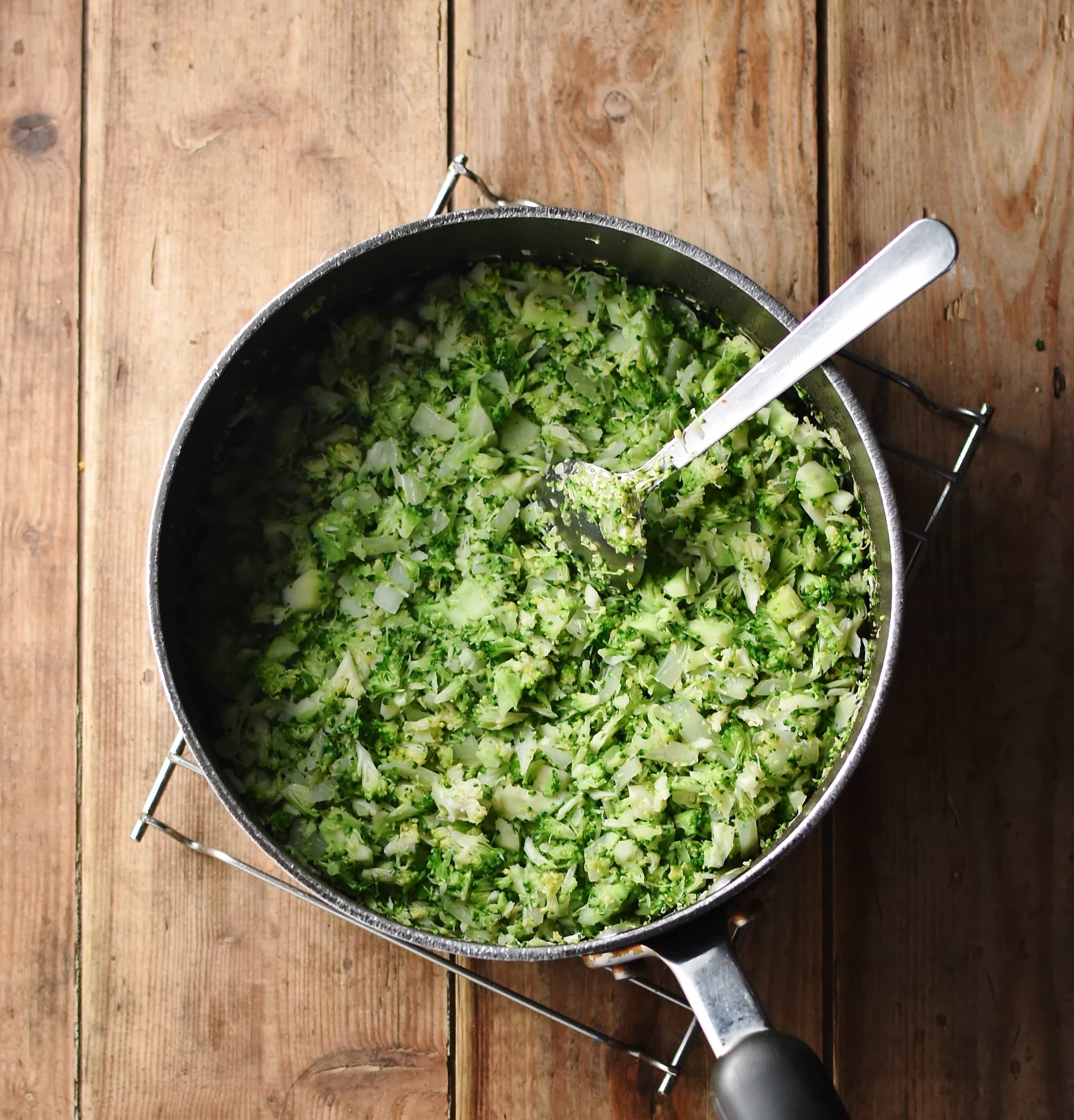 Crumbly broccoli in large pot with spoon.