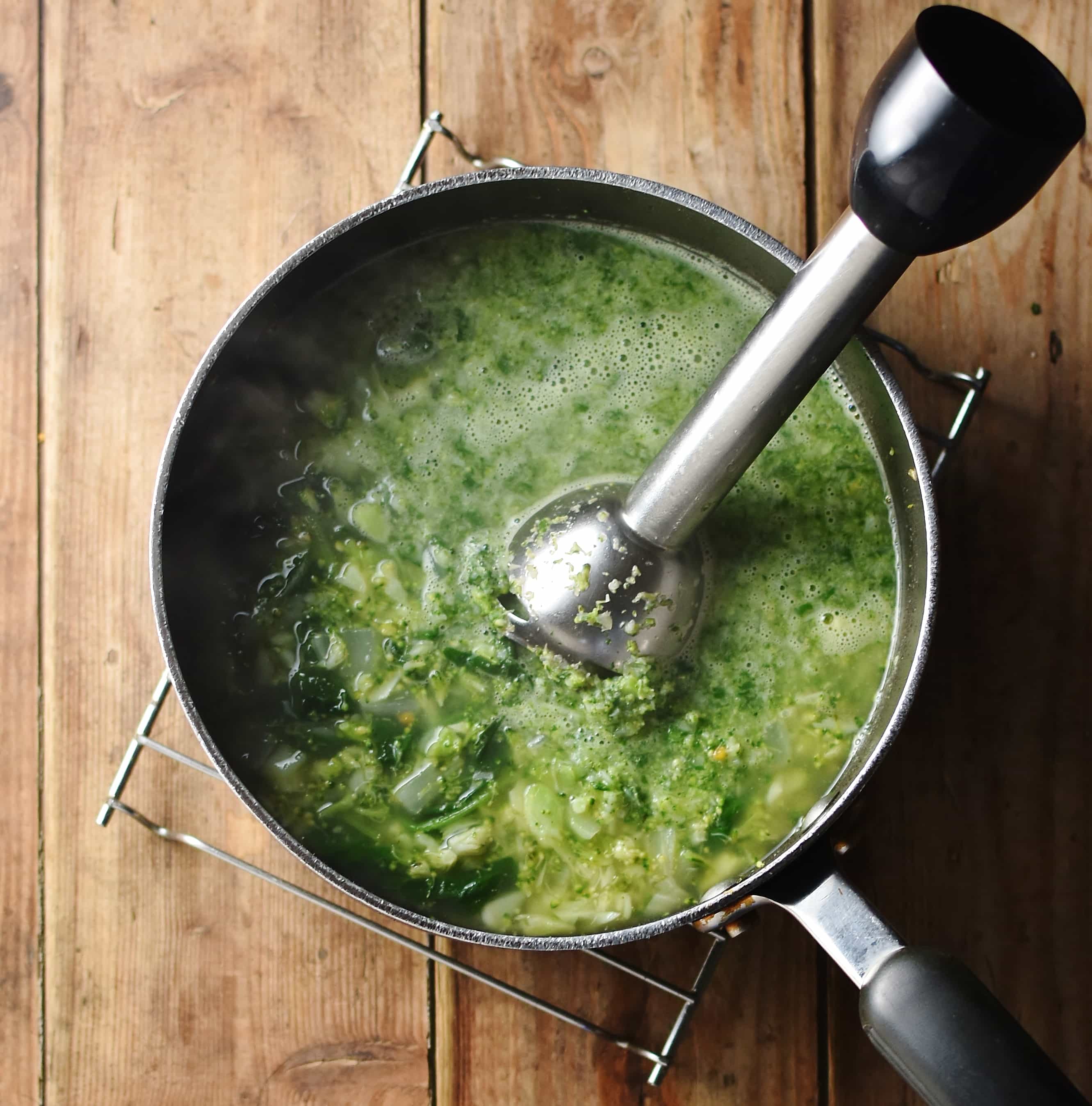 Partly pureed broccoli soup with stick blender in large pot.