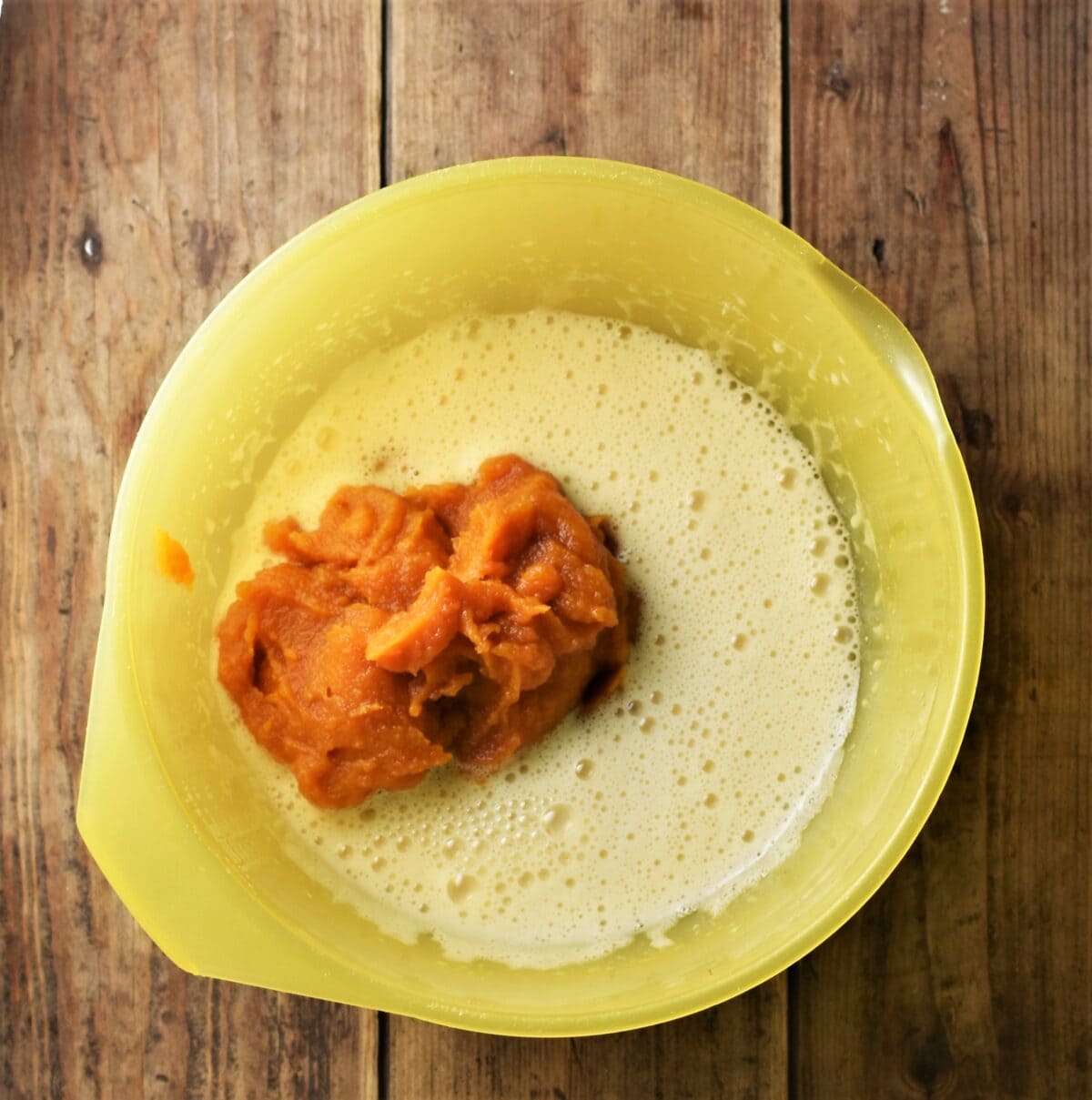 Fluffy egg mixture and sweet potato puree in large yellow bowl.