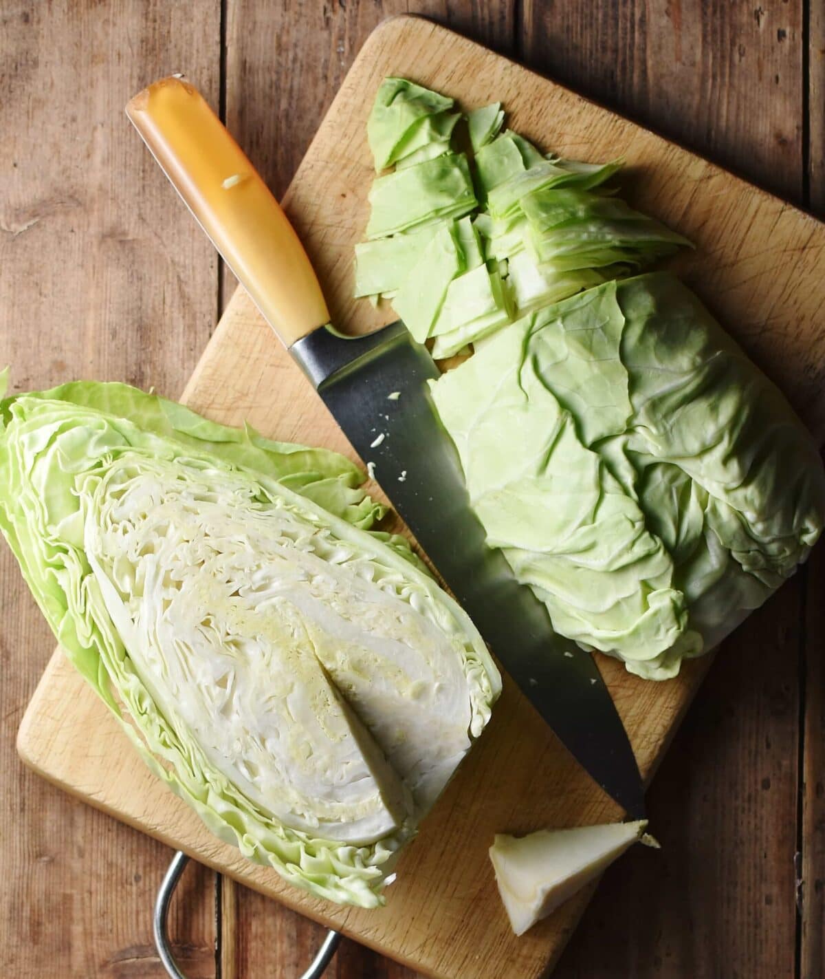 2 halves of pointed cabbage, partly chopped on cutting board with knife.