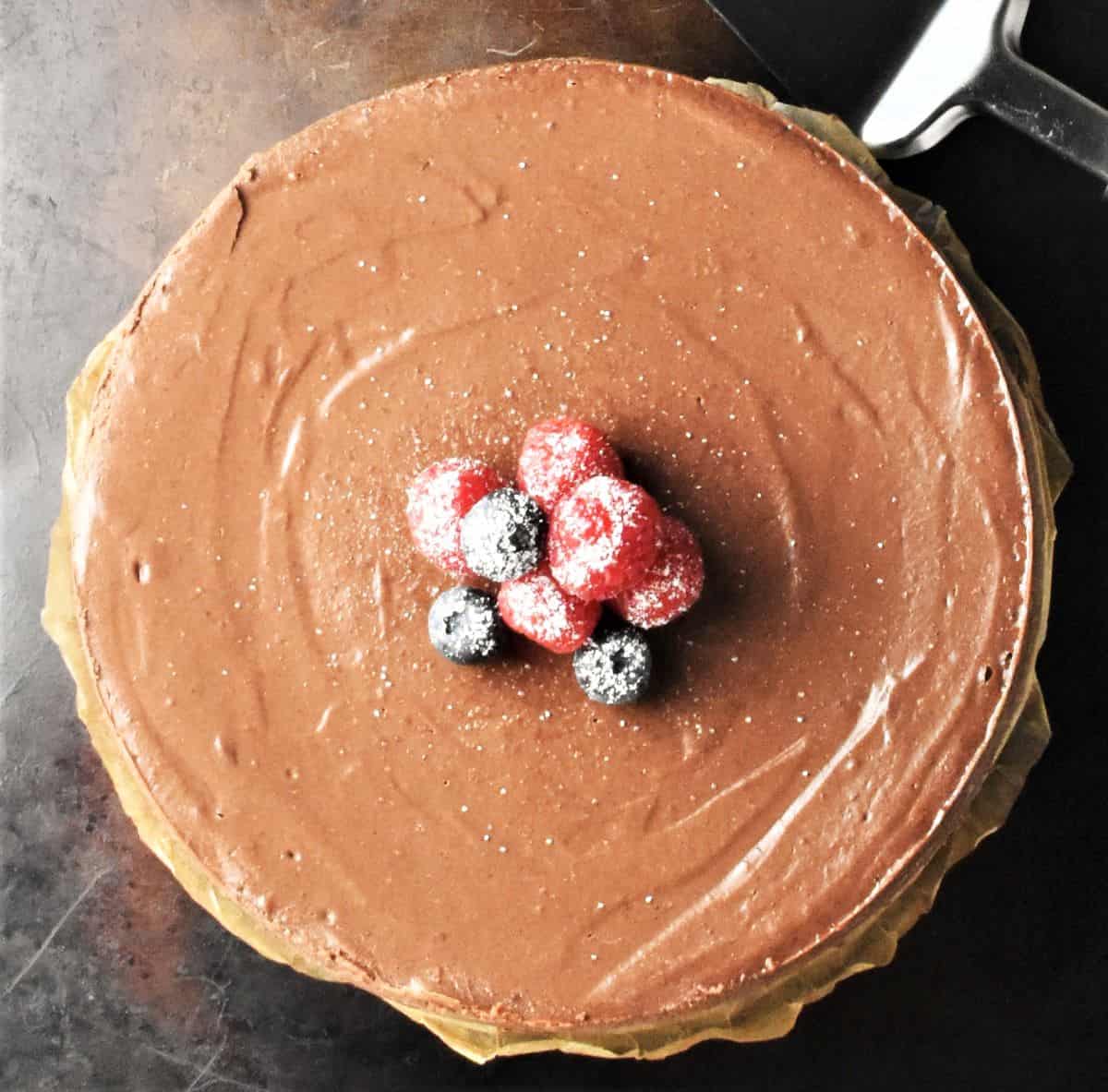Top down view of baked healthy chocolate cheesecake with fruit on top.