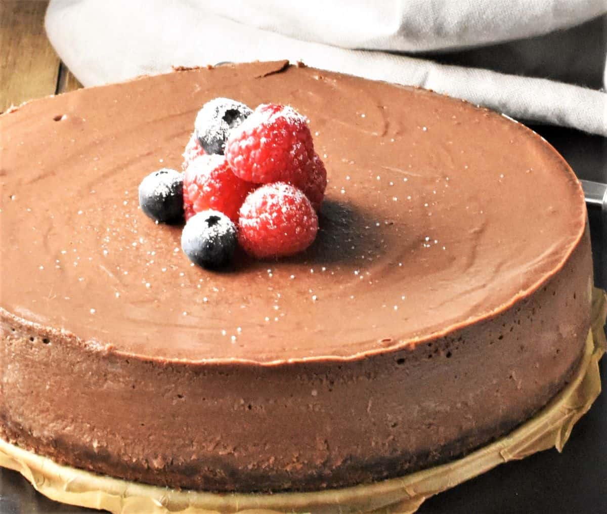 Side view of ricotta chocolate cheesecake with fruit on top.