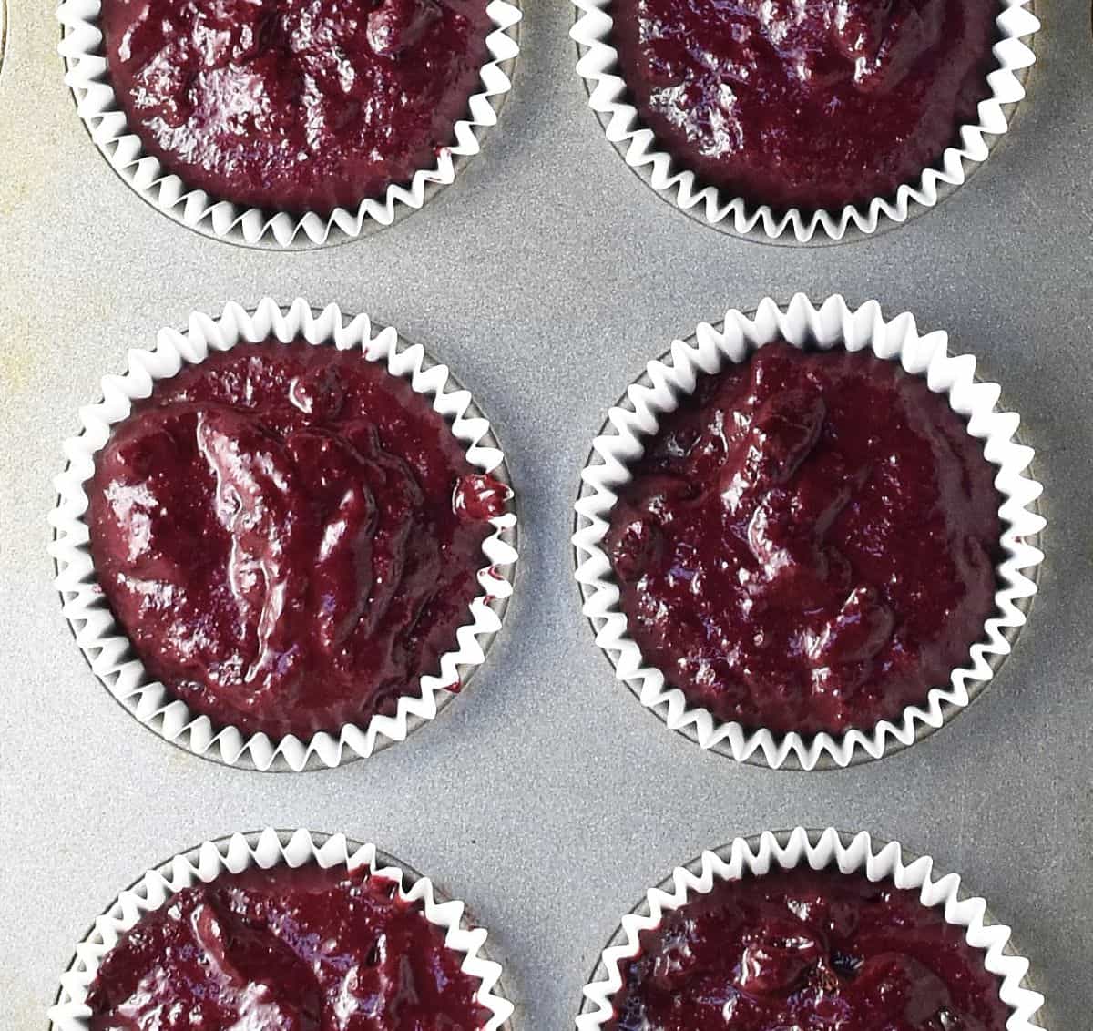 Top down view of 6 unbaked beet chocolate muffins in pan.