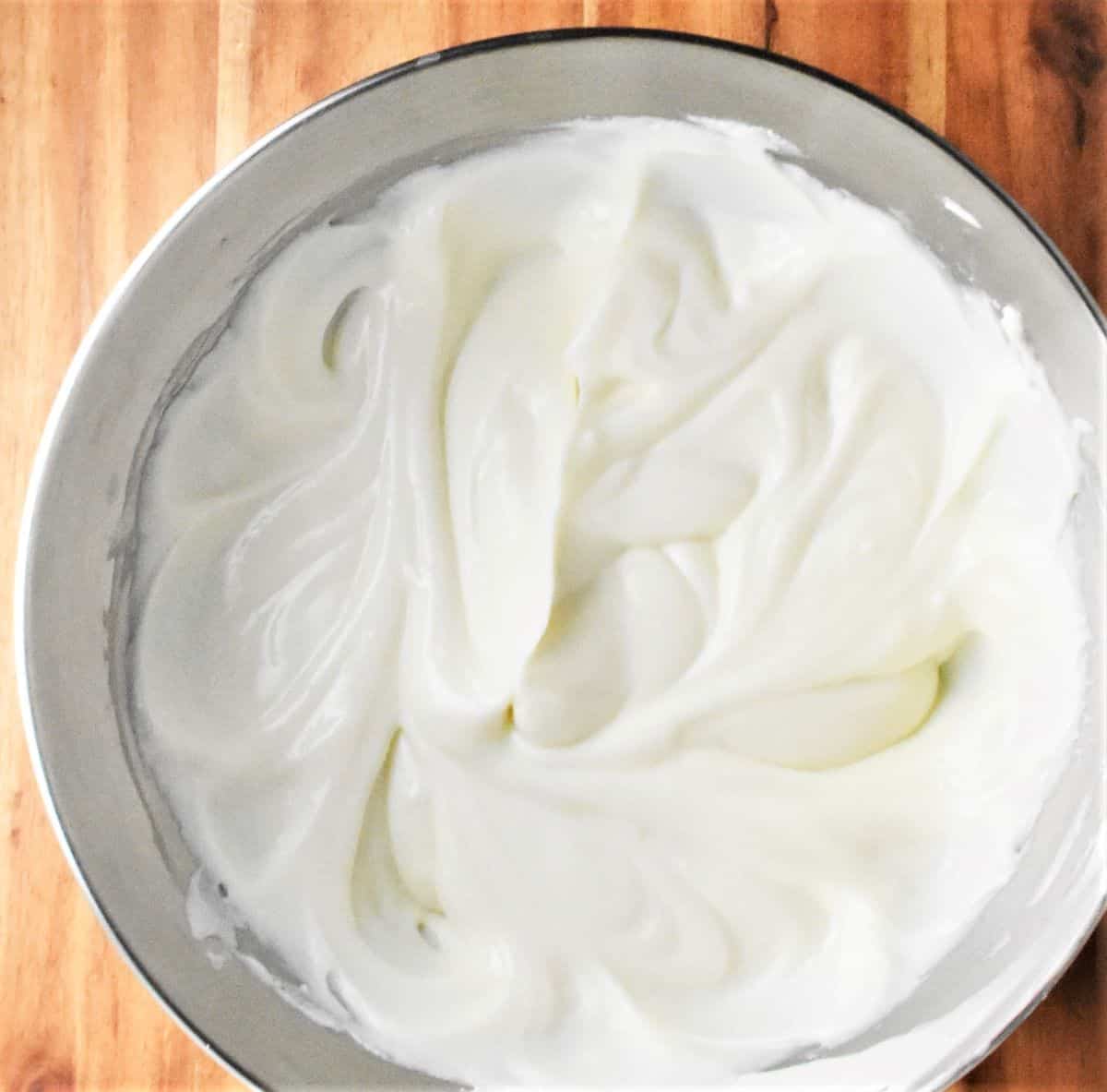 Creamy cheese mixture for cheesecake in metal bowl.