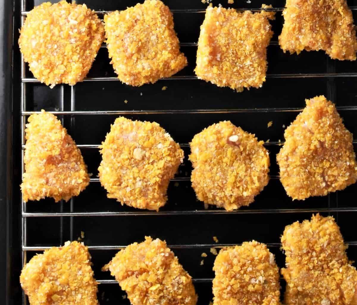 Raw cornflake chicken nuggets on top of rack.