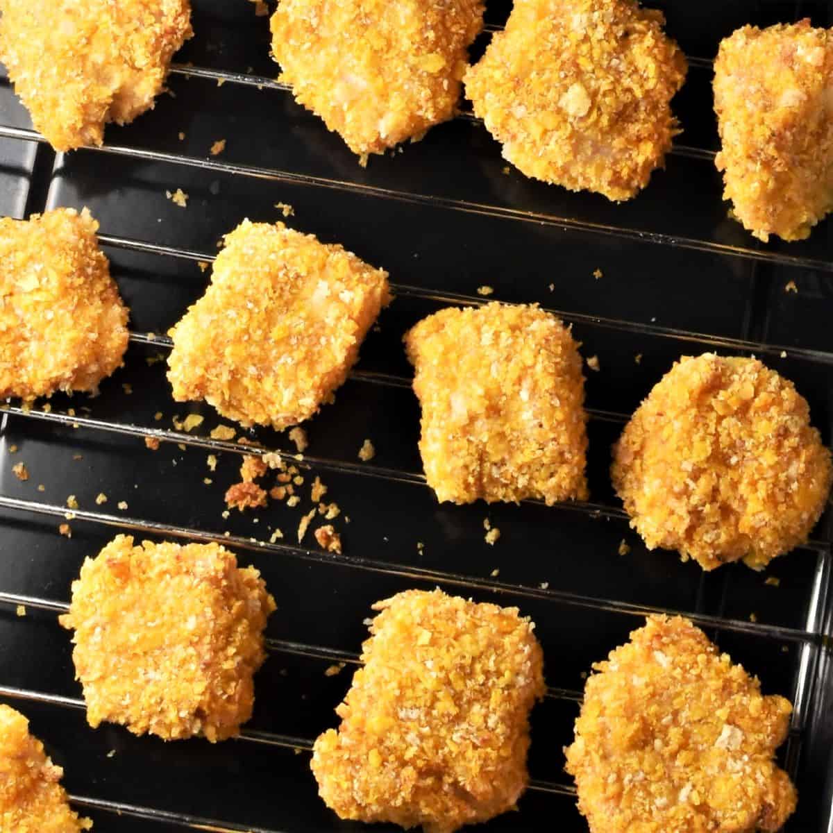 Baked crispy cornflake nuggets on top of rack.