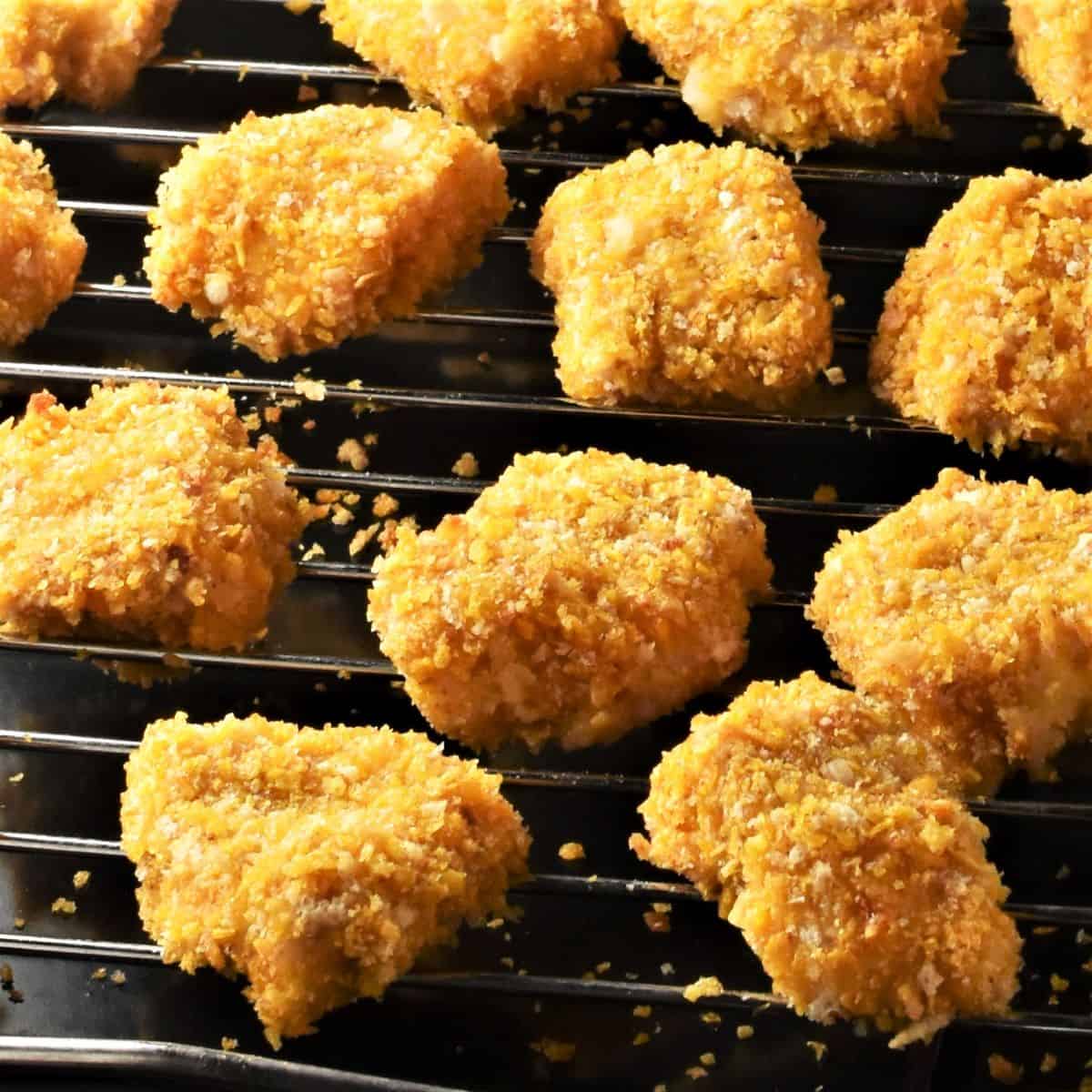Side view of crispy cornflake chicken nuggets on top of rack.
