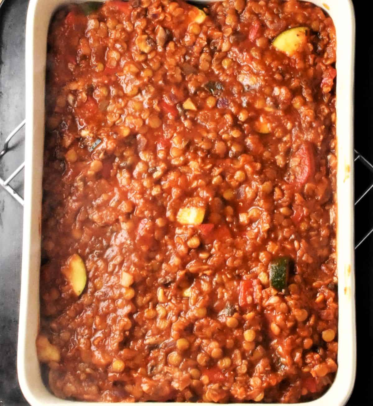 Lentil and vegetable sauce layer in lasagna dish.